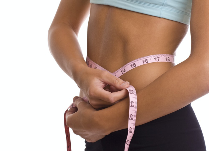 a person measuring their abdomen with a measuring tape