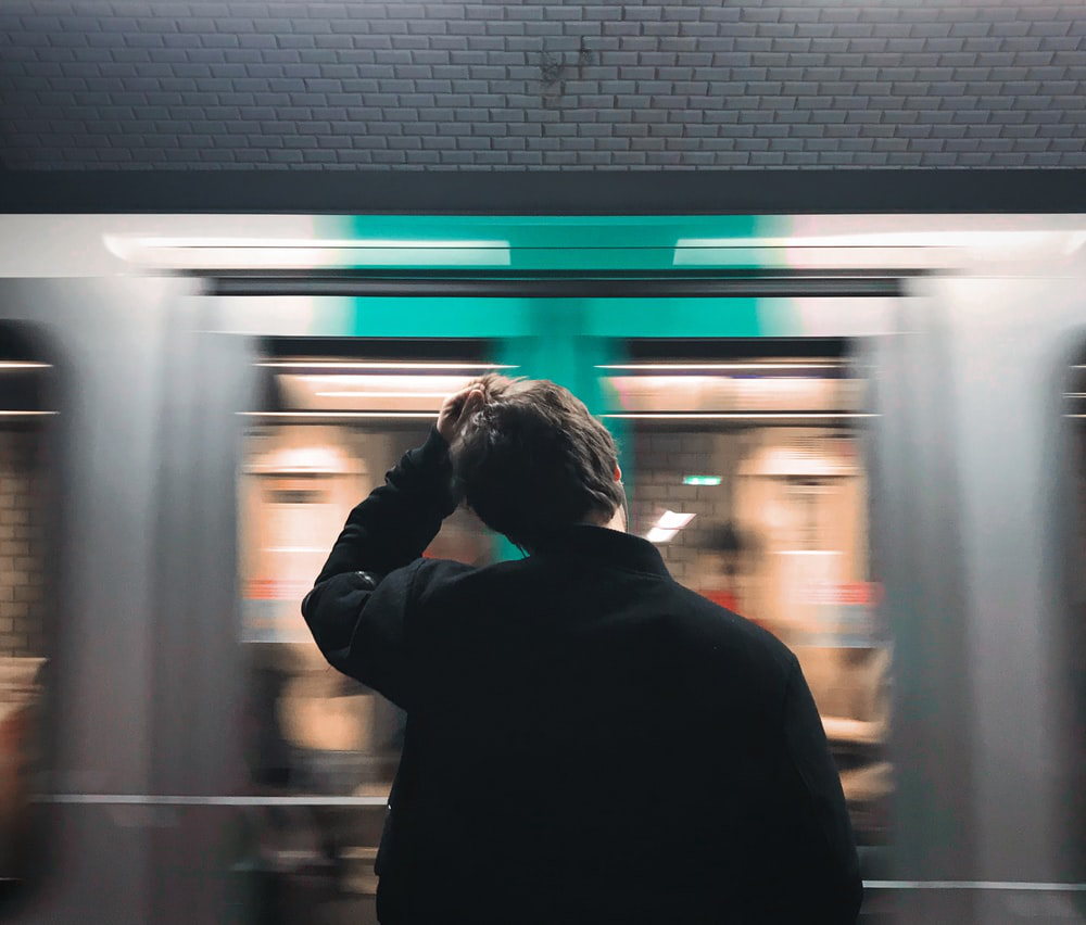 a person stands past a whirring train