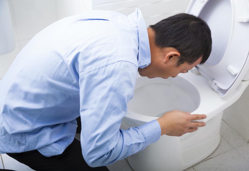 man vomitting in toilet